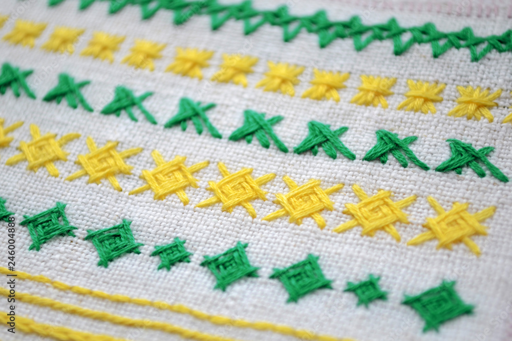 Different examples of green and yellow patterns of embroidery on white fabric