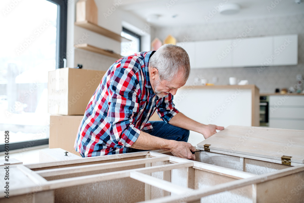 Senior man assembling furniture at home, a new home concept. Senior man assembling furniture at home, a new home concept.
