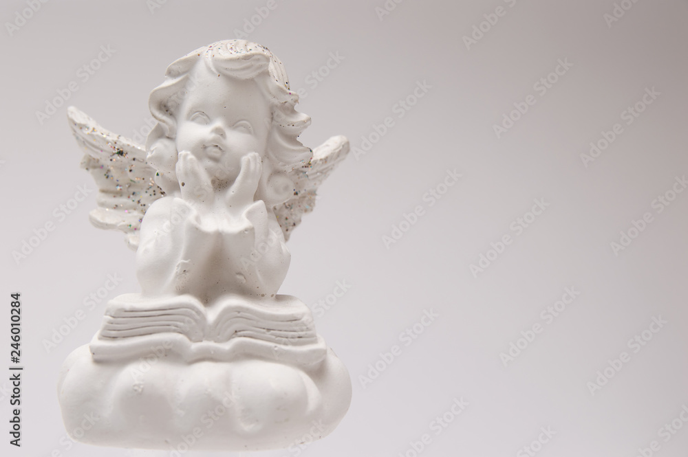 gypsum white angel on a white background reading a book and thinking gypsum white angel on a white background reading a book and thinking