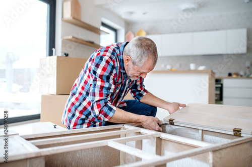 Senior man assembling furniture at home, a new home concept.