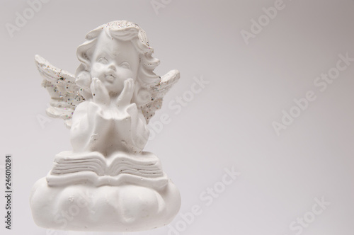 gypsum white angel on a white background reading a book and thinking