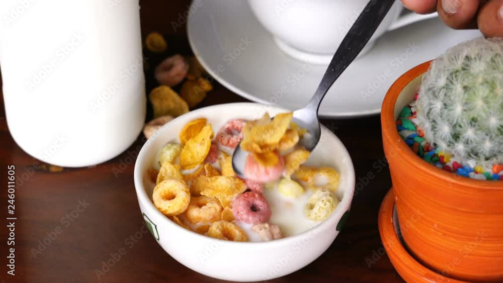 Scooping and eating cereal Corn Flakes and Froot Loops from a white bowl as a breakfast Scooping and eating cereal Corn Flakes and Froot Loops from a white bowl as a breakfast