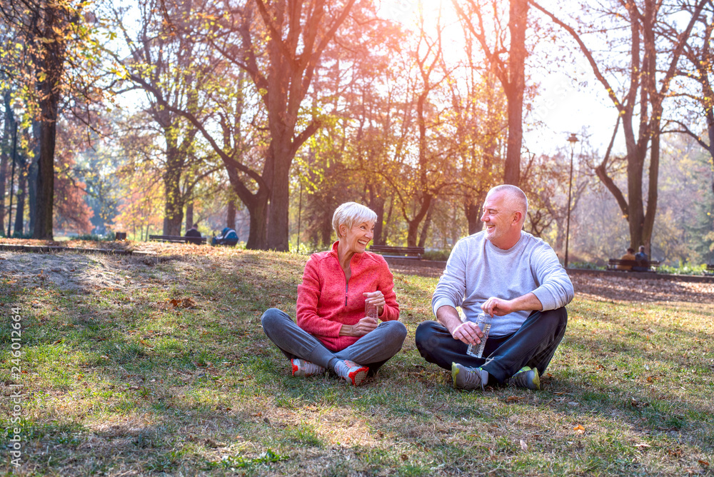 Fototapeta premium Active senior couple sitting on the ground and take a little break after training outdoor