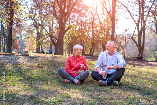 Active senior couple sitting on the ground and take a little break after training outdoor