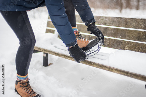 woman putting non slip snow cleat on hiking boot in winter photo