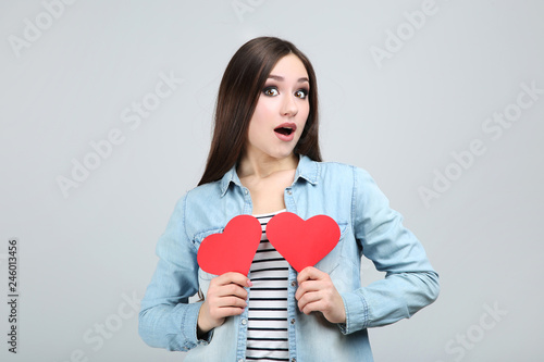 Beautiful woman holding red paper hearts on grey background
