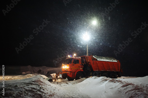 snow plow machine clears snow outside at night during snowstorm © Владимир Никонов
