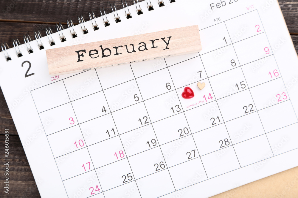 Valentine day calendar with hearts and word February on wooden table Valentine day calendar with hearts and word February on wooden table
