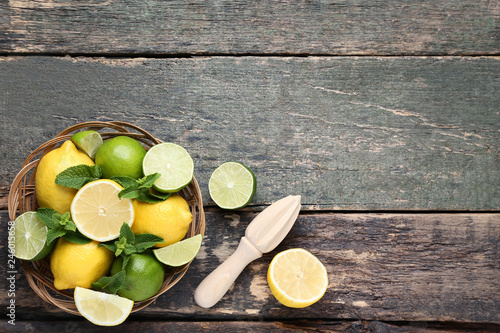 Lemons and limes with mint leafs in basket on wooden table