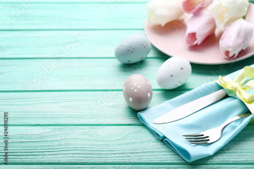 Kitchen cutlery with easter eggs and tulip flowers on mint wooden table