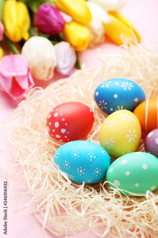 Colorful easter eggs in nest on pink background