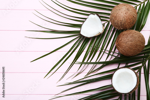 Ripe coconuts with palm leafs on pink wooden table