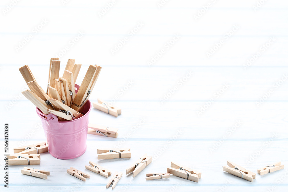Obraz premium Brown clothespins in pink bucket on wooden table