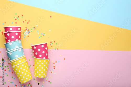 Paper cups with confetti on colorful background