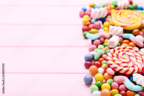 Sweet candies and lollipops on pink wooden table