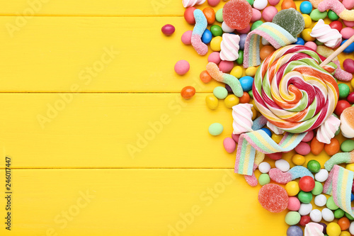 Sweet candies and lollipops on yellow wooden table