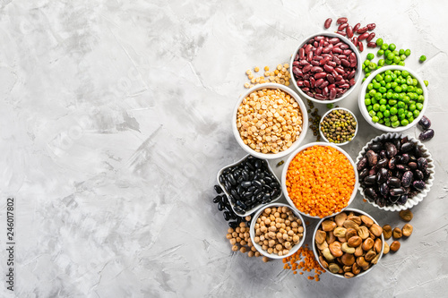 Selection of legumes - beans, lentils, mung, chickpea, pea in white bowls on stone background photo