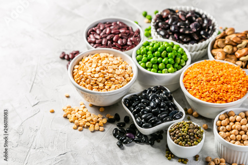 Selection of legumes - beans, lentils, mung, chickpea, pea in white bowls on stone background photo