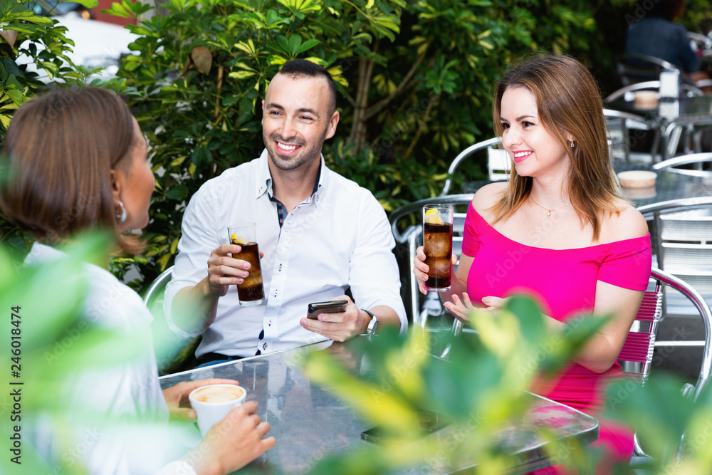 Fototapeta premium Young man with two females are playful talking in time lunch in cafe.