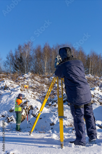 Surveyor with an assistant do a geodetic survey at a construction site
