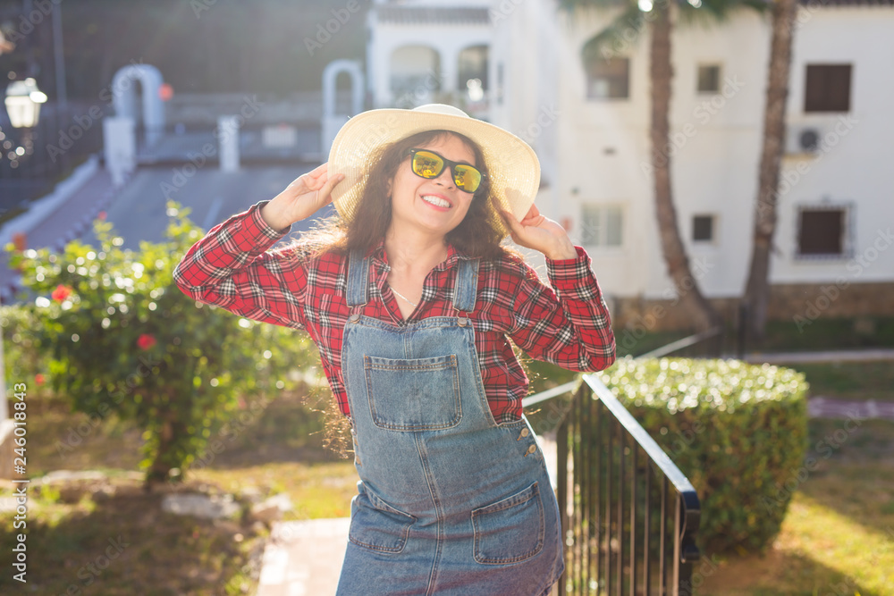 Travel, summer and vacation concept - happy young woman in hat smiling over the hotel background