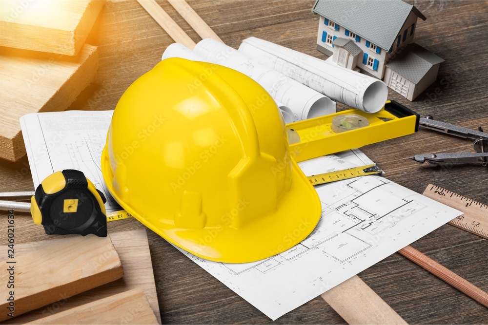Yellow hard hat and blueprints on wooden desk in a construction Stock ...