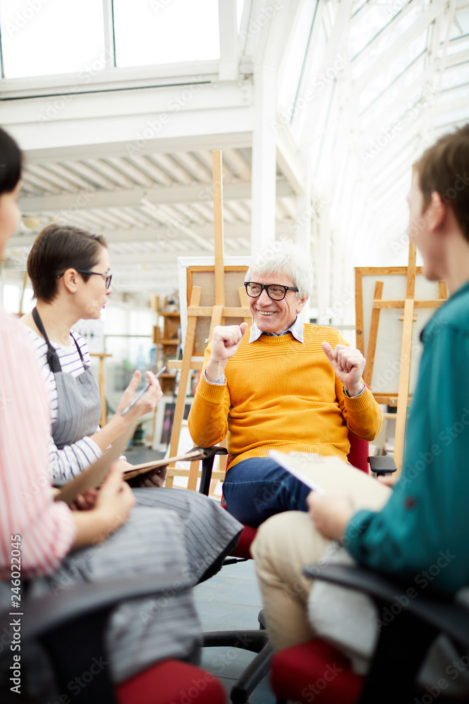 Obraz premium Portrait of joyful mature art teacher talking to group of students sitting in circle in art studio