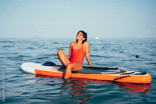 Canvas-taulu Young woman doing yoga on sup board with paddle