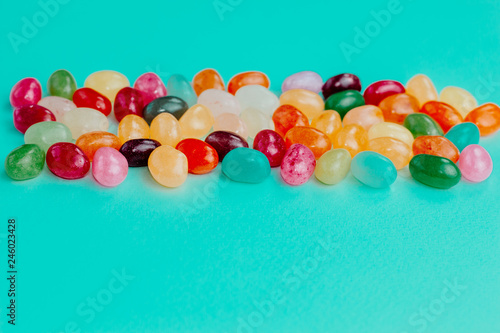 Colorful bean sweet candies on bright turquoise blue background. Easter concept. Close up. Copy space.