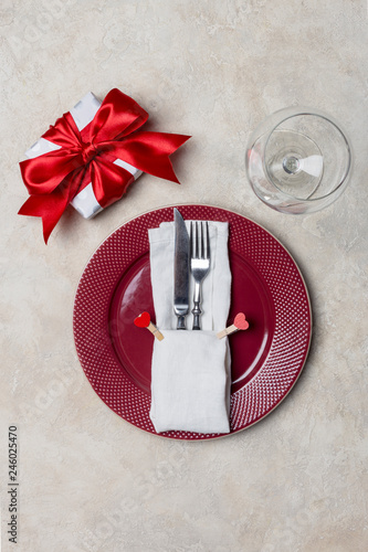 Red plate with gift box, with fork, knife and white napkin at white background