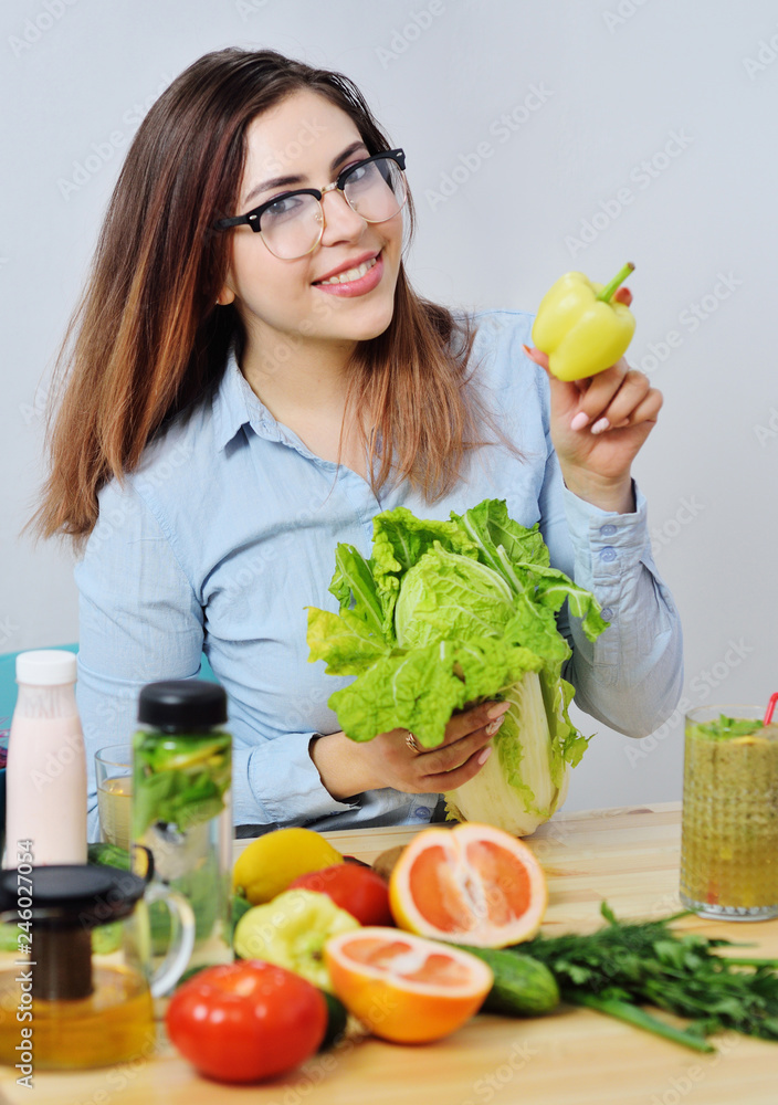 beautiful young girl holding bell peppers and cabbage in the background of a table with vegetables. Healthy food beautiful young girl holding bell peppers and cabbage in the background of a table with vegetables. Healthy food