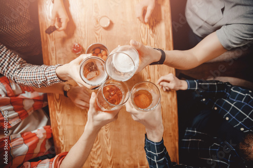 Canvas Print Cheerful and happy old friends are drinking draft beer at pub bar clink glasses