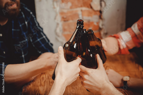 Friends of men drink beer in dark bottles on bar pub, check. Friendship concept