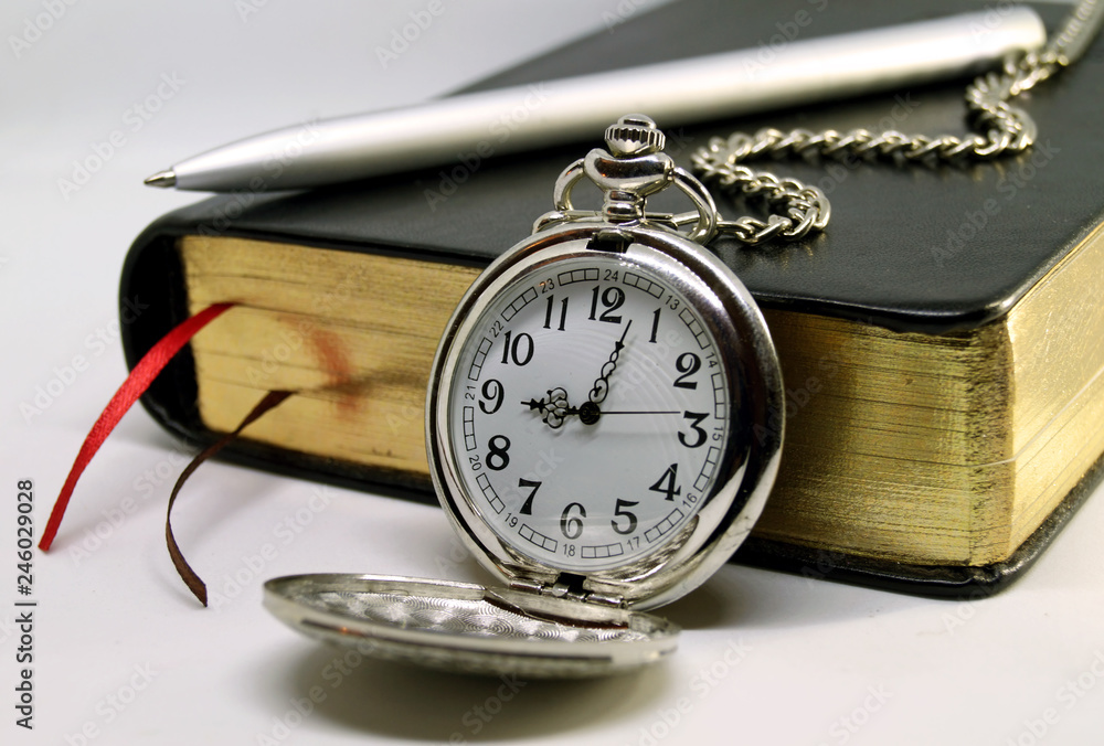Diary with pen and pocket watch on white background.