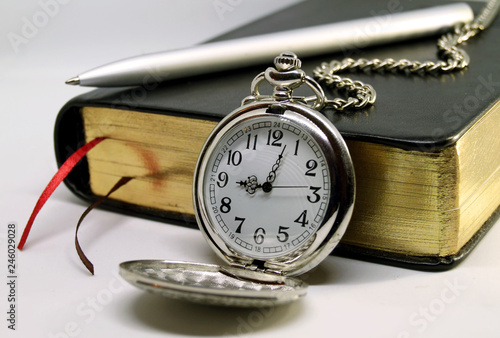 Diary with pen and pocket watch on white background.