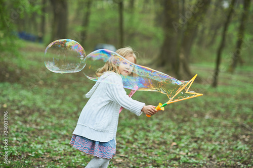 girl playing with giant soap bubble. Girl blowing large bubbles