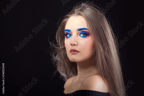Attractive brunette with bright stylish make-up. Colored Smokey eyes and blue eyebrows.