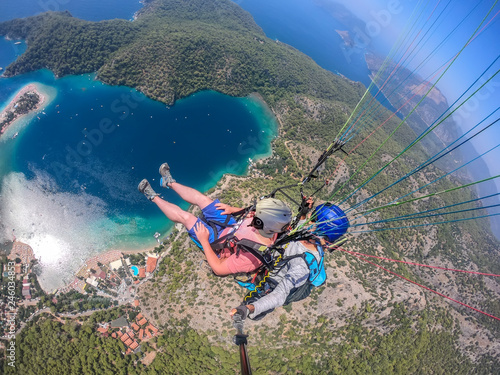 Paragliding in the sky. Paraglider tandem flying over the sea with blue water and mountains in bright sunny day. Aerial view of paraglider and Blue Lagoon in Oludeniz, Turkey. Extreme sport. Landscape