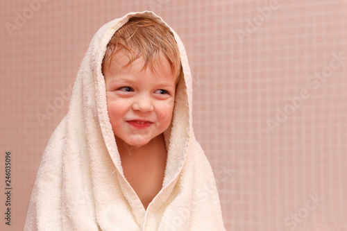 Adorable baby boy sitting under a hooded towel after bath.