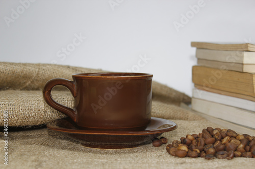 Coffee cup on burlac, with book and blur background