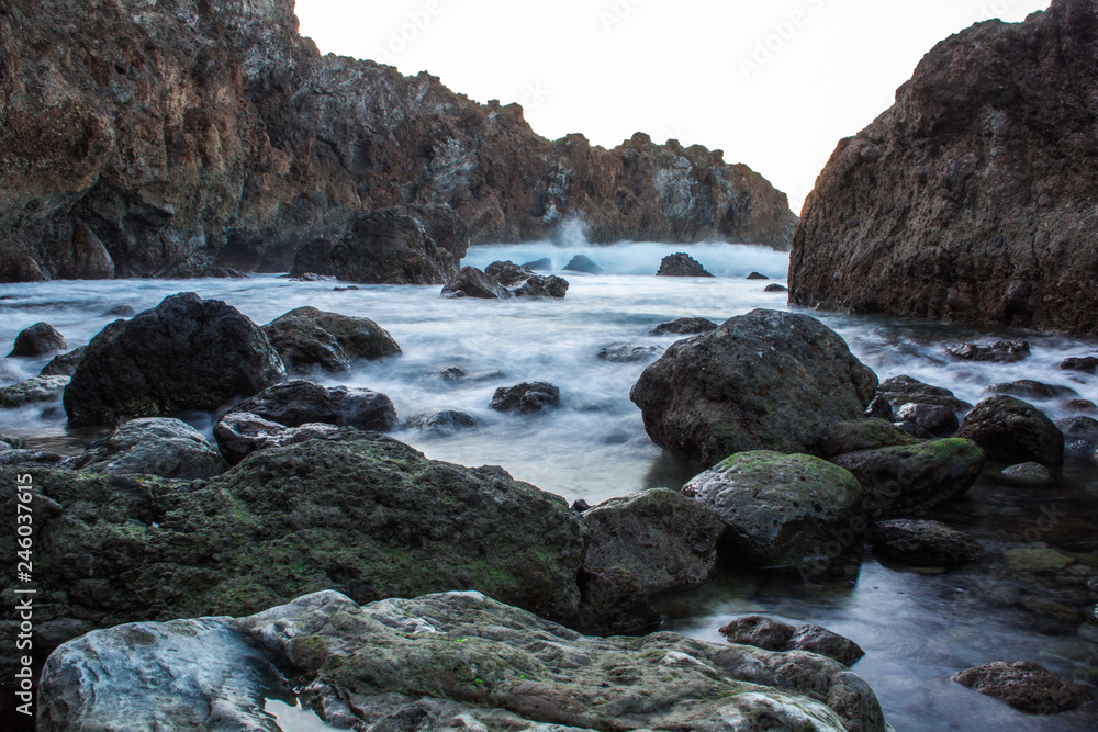 rocky beach with moss and black sand. Volcano stones in a natural pool at Tenerife North 