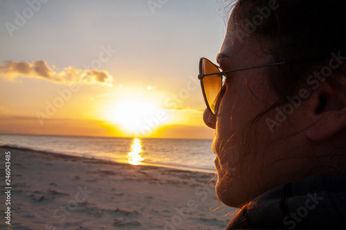 Woman silhouette over an horizon dominated by the sunset over the Cuban Islands at Cayo Levissa. Amazing sunset reflected onto the girl face with sunglasses while the sun goes down on an idyllic beach © abriendomundo
