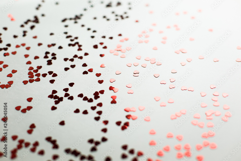  Small red sparkling hearts are scattered on a white background in soft focus. A good shot for an article about love and Valentine's Day or wedding