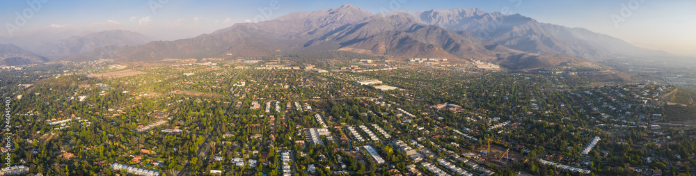 Amazing aerial views of Santiago de Chile city during the sunset with the Andes mountain range making a wonderful horizon line. Urban planning of Santiago from above, streets, trees, houses and parks