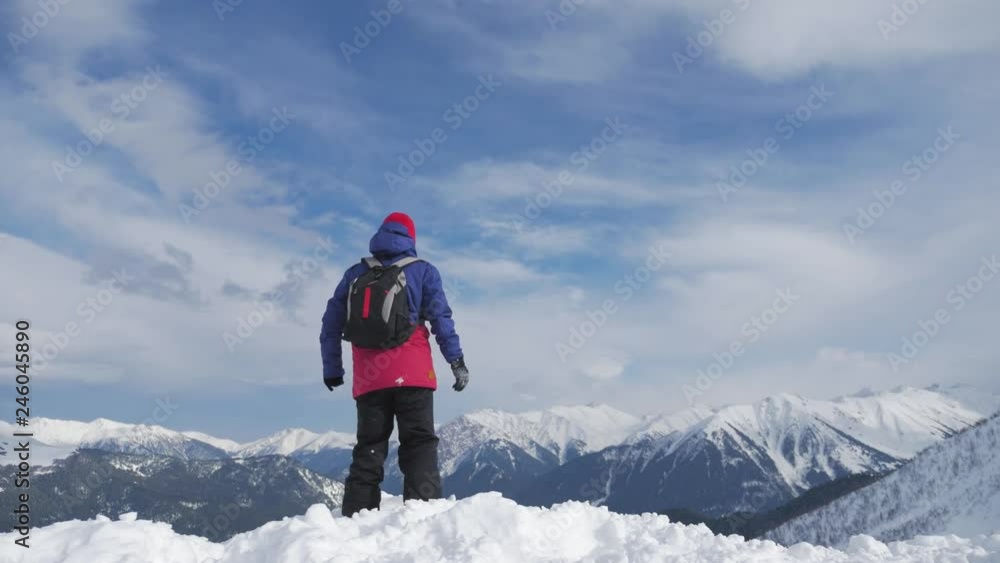 Man with backpack standing on snowy mountain top in winner pose with raised hands enjoying view and achievement on bright sunny winter day. Concept adventure, outdoors activities, healthy lifestyle. Man with backpack standing on snowy mountain top in winner pose with raised hands enjoying view and achievement on bright sunny winter day. Concept adventure, outdoors activities, healthy lifestyle.