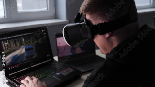 Young guy (male) player in virtual glasses plays (relaxes) against him 2 game monitors, he moves his hands seeing the movement with glasses. Concept of: Lifestyle, Underworld, 3d, Virtual reality © dkHDvideo