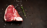 Raw meat steak with seasoning on concrete background. Space for text. Beef T-bone steak, top view. Barbecue concept. Ingredients for roasting meat.