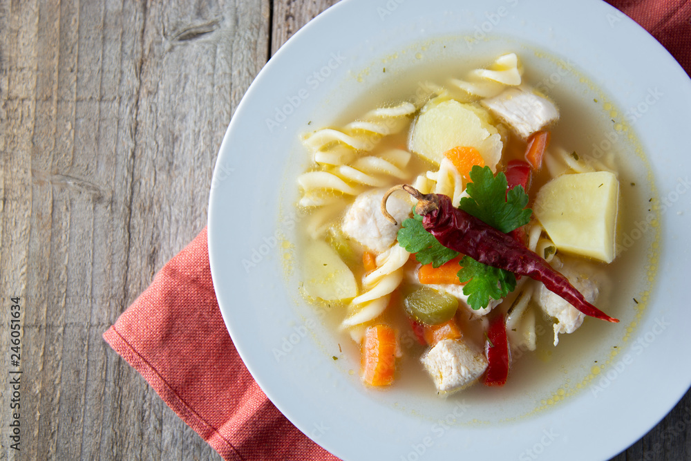 Chicken soup with noodles and vegetables, rustic wooden background. Healthy homemade food. Top view. Square iamge. Chicken soup with noodles and vegetables, rustic wooden background. Healthy homemade food. Top view. Square iamge.