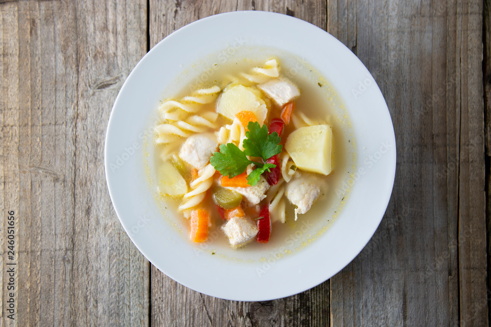 Chicken soup with noodles and vegetables, rustic wooden background. Healthy homemade food. Top view. Square iamge. Chicken soup with noodles and vegetables, rustic wooden background. Healthy homemade food. Top view. Square iamge.