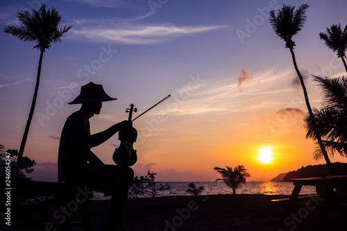 Local musicians, Asian man playing violin on the coconut beach at sunrise